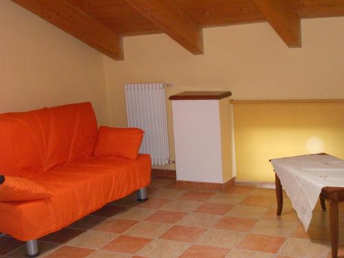 a living room with an orange couch and a table at Agriturismo Monrabbioso in Cereseto
