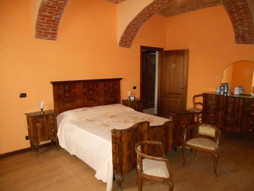 a bedroom with a bed with wooden furniture and chairs at Agriturismo Monrabbioso in Cereseto