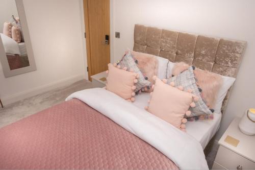 a bed with pink and grey pillows on it at Ashwoods House in Enniskillen