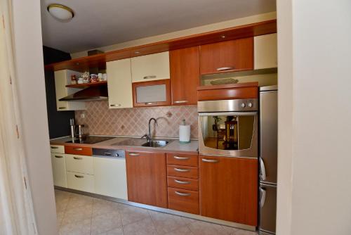 een keuken met houten kasten en roestvrijstalen apparatuur bij Apartment Nelly- self check-in in Zadar