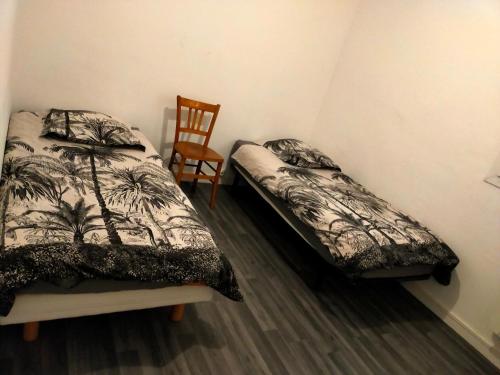 a bedroom with two twin beds and a chair at Appartement en duplex au 3ième étage sans ascenseur in Hyères