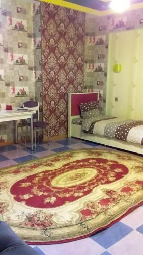 a large rug on the floor in a room with two beds at Tubram S Ailəvi Qonaq Evi in Sheki