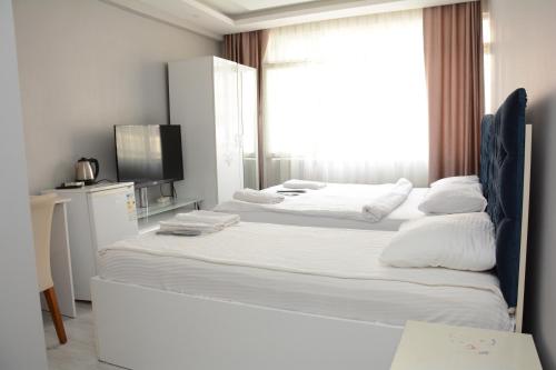 a white bedroom with two beds and a window at palmiye suıt otel in Istanbul