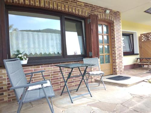 a patio with two chairs and a table in front of a window at Helena Ferienwohnung in Hemfurth-Edersee