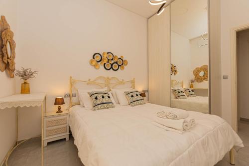 1 dormitorio con 1 cama blanca grande y espejo en Foivos Apartment, en Naxos Chora