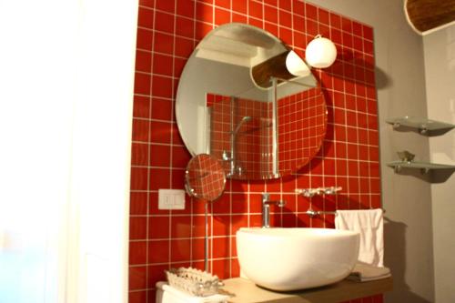 a red tiled bathroom with a sink and a mirror at B&B La Torre a Revere in Revere