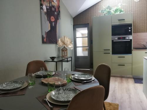 a dining room with a table and chairs and a kitchen at La Canopée in Cholet