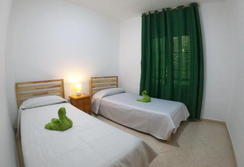 グラン・タラハルにあるApartamento junto la playaのベッド2台(緑のぬいぐるみを乗せた部屋)