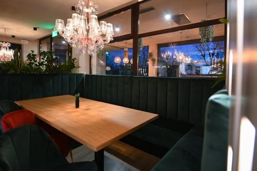 a wooden table in a restaurant with a chandelier at Hotel Xemar in Arad