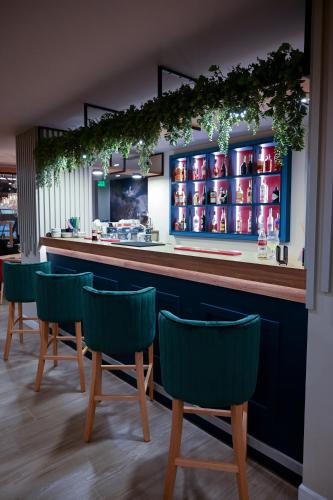 a bar with green chairs in a restaurant at Hotel Xemar in Arad