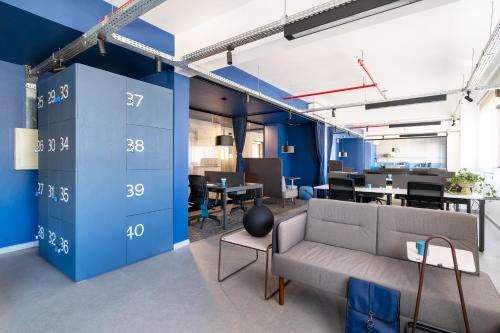 an office with blue walls and a couch and tables at Swan Generation Porto Alegre in Porto Alegre