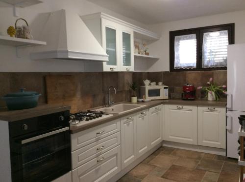 una cucina con armadi bianchi, lavandino e piano cottura di Casa Vacanze Marinella a Marinella di Selinunte