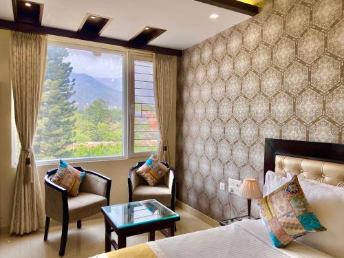 um quarto com uma cama, 2 cadeiras e uma janela em Green View by Green Tree Hotels em Rishikesh