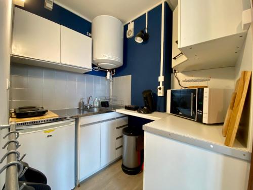 une petite cuisine avec des armoires blanches et un micro-ondes dans l'établissement Suite au pied des pistes - Pla d'Adet, à Saint-Lary-Soulan