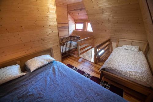 a bedroom with two beds in a wooden cabin at Šumska priča Tara / A Forest Tale Tara in Mokra Gora