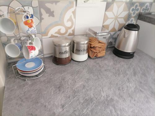 a kitchen counter with cups and plates and trash cans at SoleLuna in Santa Elisabetta