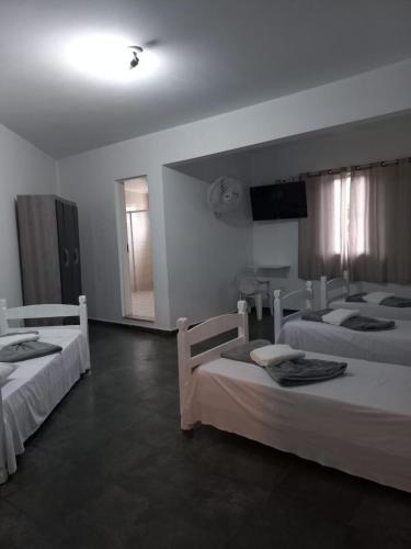 a bedroom with two beds and a television in it at PLANALTO HOTEL II in Arujá