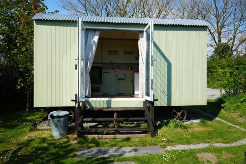 a green shed with a kitchen inside of it at Hillcrest Hut in Tenby