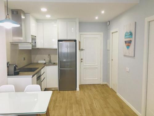 a kitchen with white cabinets and a stainless steel refrigerator at Apartamento a 50 mts playa con piscina en Blanes muy céntrico y acogedor. in Blanes