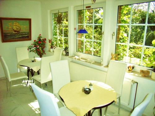 a restaurant with tables and white chairs and windows at Ostsee Hotel-Pension An der Lindenallee in Bad Doberan