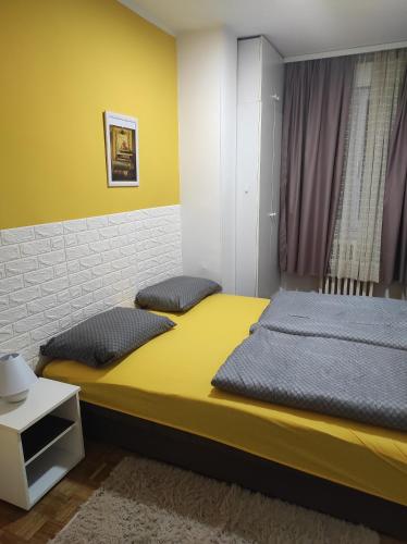 Duas camas num quarto com paredes amarelas e brancas em apartman Liman em Novi Sad