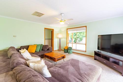 a living room with a couch and a flat screen tv at The Clydesdale - Spacious 4 bedroom Home in Echuca