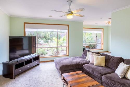 a living room with a couch and a flat screen tv at The Clydesdale - Spacious 4 bedroom Home in Echuca