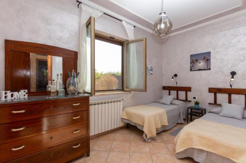 a bedroom with two beds and a dresser and a window at Villetta indipendente vicino aeroporto in Fiumicino