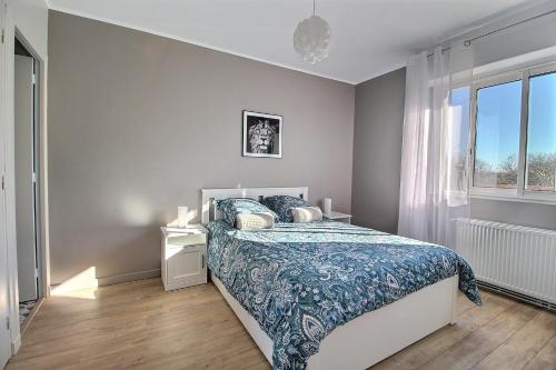 um quarto com uma cama com uma colcha azul e uma janela em ÉPIPAPU Appartement 57 M2 - Parking privé - Loggia - em Bourges