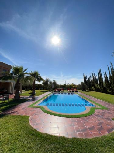 a swimming pool in a park with palm trees at Villa Haitam Marrakech in Oubadine