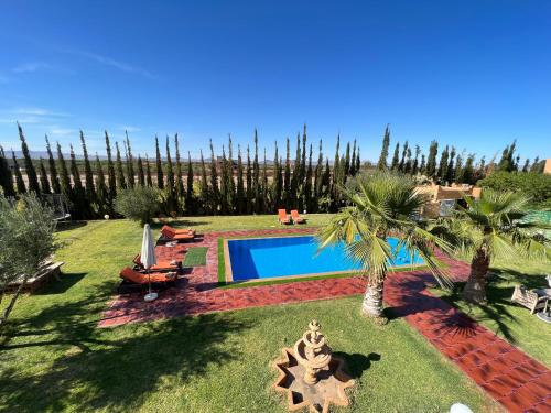 a backyard with a swimming pool and palm trees at Villa Haitam Marrakech in Oubadine