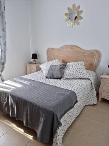 una camera da letto con un letto con una coperta grigia e uno specchio di AGRADABLE ADOSADO CON PISCINA a Ciudad Quesada