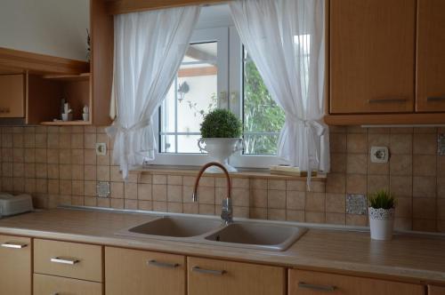 eine Küche mit einem Waschbecken und ein Fenster mit Vorhängen in der Unterkunft Nostos House in Triovasálos