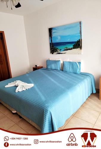 Un dormitorio con una cama azul con una foto del océano en Sunset Waves, en Roatan