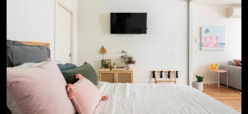 a living room with a bed with pink pillows at The Pas.Coe - A Stylish 1 bedroom unit with free parking. in Melbourne