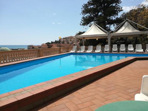 a large swimming pool with chairs and a gazebo at Hotel Miramare in Imperia
