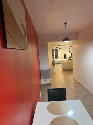 une salle à manger avec une table blanche et un mur rouge dans l'établissement Gite spatieux,cour,entree autonome, à Agen