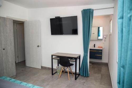 a room with a table and a television on a wall at Hotel Oasis-Dream Holidays - La Petite France in San Bernardino