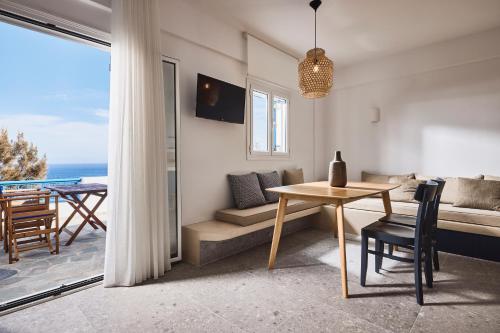 Sala de estar con mesa y vistas al océano en Tramontana Suites, en Áyios Stéfanos
