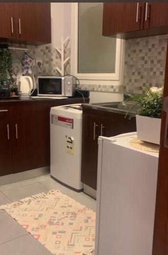 La cuisine est équipée d'un réfrigérateur blanc et d'un four micro-ondes. dans l'établissement شقة في مدينة الملك عبدالله الاقتصادية حي الشروق, à King Abdullah Economic City