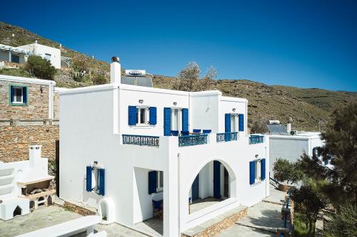 a white building with blue doors and windows at Tramontana Suites in Áyios Stéfanos