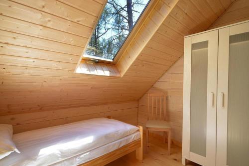 Cabaña de madera con cama y ventana en Holiday resort in Pobierowo for 6 persons, en Pobierowo