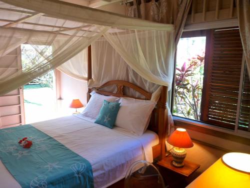 a bedroom with a canopy bed and a window at Poerani Moorea in Moorea