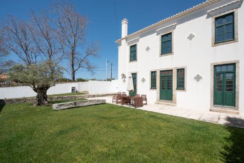 a white house with a green door and a yard at Casas São João by Ana Ferro Rentals in Arcozelo