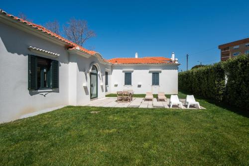 a white house with chairs and a patio at Casas São João by Ana Ferro Rentals in Arcozelo
