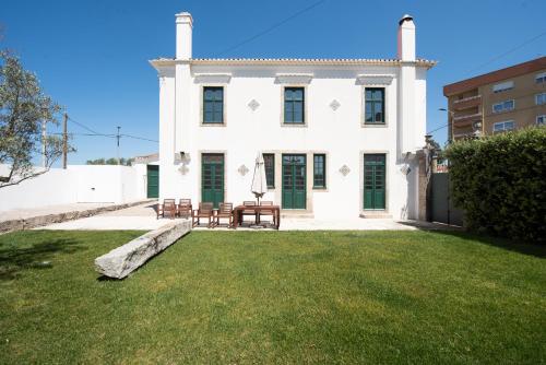 a white house with chairs and a lawn at Casas São João by Ana Ferro Rentals in Arcozelo
