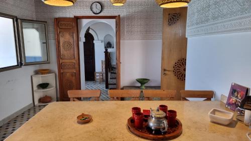une chambre avec une table, des chaises et une horloge dans l'établissement Dar Jean, à Assilah