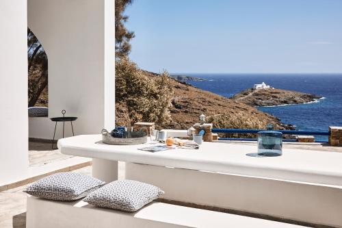 a white table with pillows on a balcony overlooking the ocean at Tramontana Suites in Áyios Stéfanos