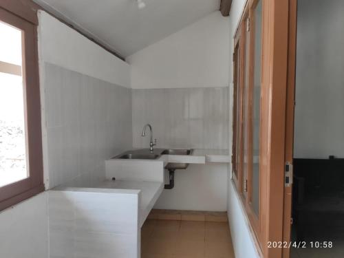 a white bathroom with a sink and a window at Kelana 2 Nice Homestay (5 Bed Rooms) Semarang in Semarang