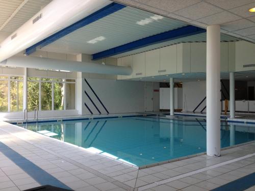 een groot zwembad met blauw water in een gebouw bij Appartement Baken in Hollum